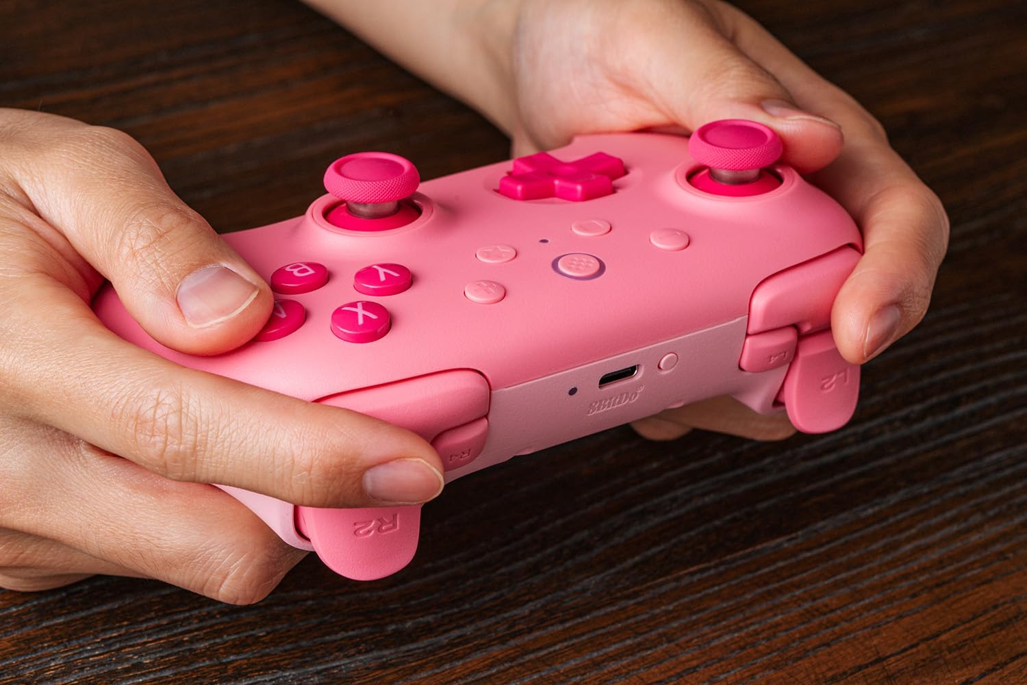Hands holding pink gaming controller